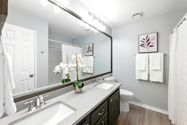 7419 Dallas Dr, Austin, TX 78729 - bathroom featuring wood finished floors, double vanity, toilet, baseboards, and curtained shower