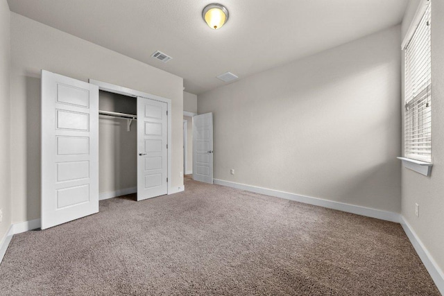 unfurnished bedroom with a closet, baseboards, carpet flooring, and visible vents