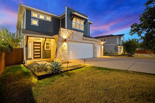 view of front of home featuring a garage, fence, stone siding, a lawn, and driveway