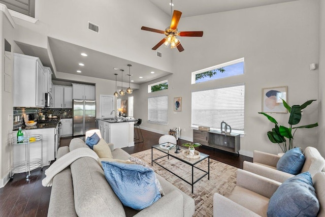 living area with baseboards, dark wood-type flooring, and a towering ceiling