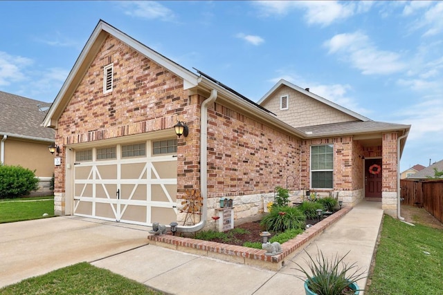 view of front of house featuring fence, an attached garage, driveway, and brick siding