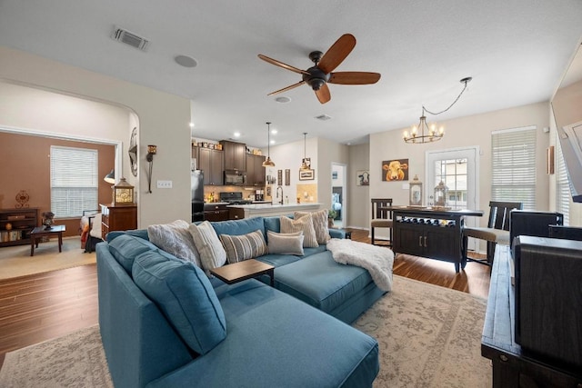 living room with visible vents, ceiling fan with notable chandelier, and wood finished floors