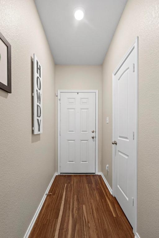 doorway with dark wood-style flooring and baseboards