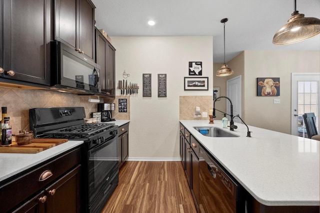 kitchen featuring a peninsula, wood finished floors, a sink, backsplash, and black appliances