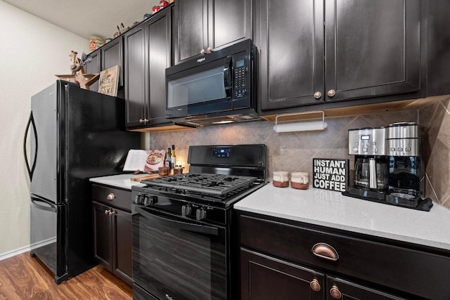 kitchen featuring wood finished floors, baseboards, light countertops, backsplash, and black appliances