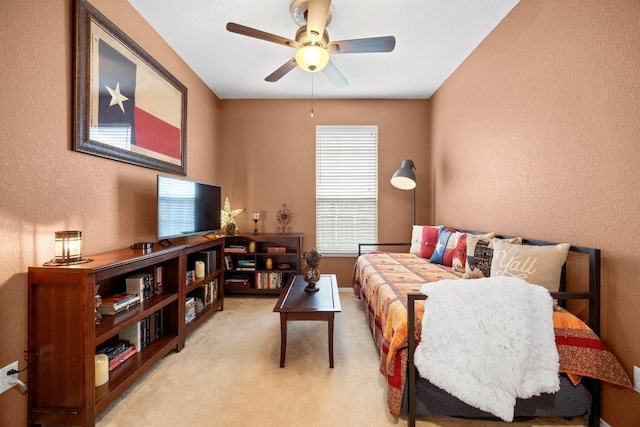 interior space with a textured wall, a ceiling fan, and light colored carpet