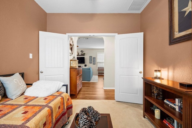 bedroom featuring visible vents, arched walkways, and light wood-type flooring