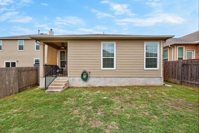 back of property featuring a fenced backyard, a ceiling fan, and a yard