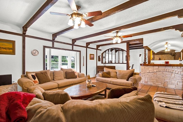living area featuring a textured ceiling, ceiling fan, and beam ceiling