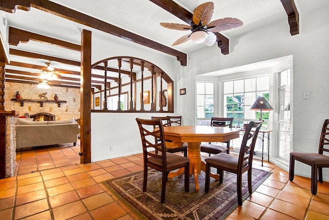 dining space featuring light tile patterned flooring, beamed ceiling, a ceiling fan, and a textured ceiling