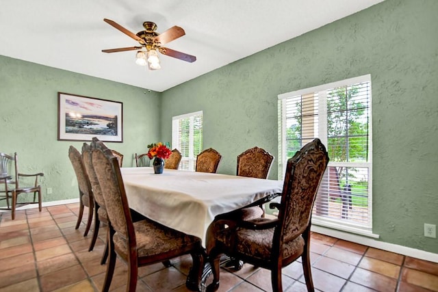 dining area with baseboards, a textured wall, ceiling fan, and tile patterned flooring