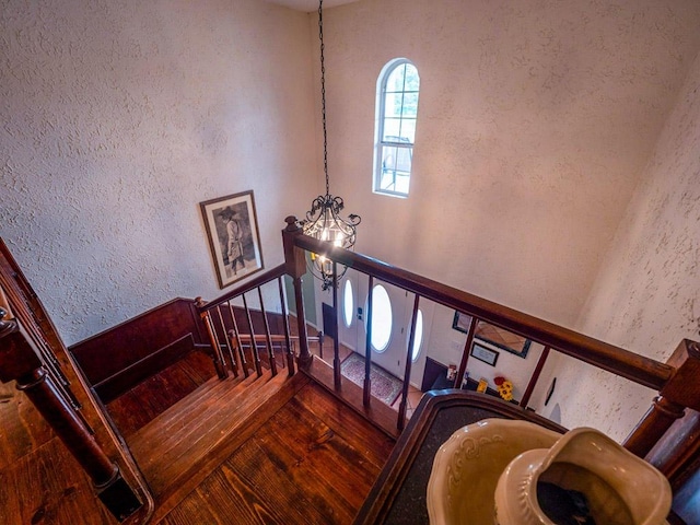 staircase featuring a textured wall and a notable chandelier