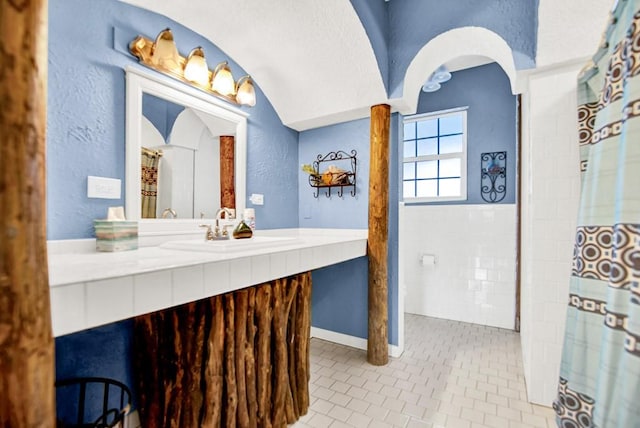 bathroom with tile patterned flooring, a textured wall, curtained shower, and vanity