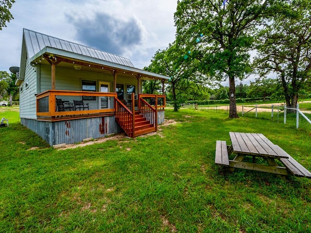 rear view of property featuring a lawn, fence, stairs, and metal roof