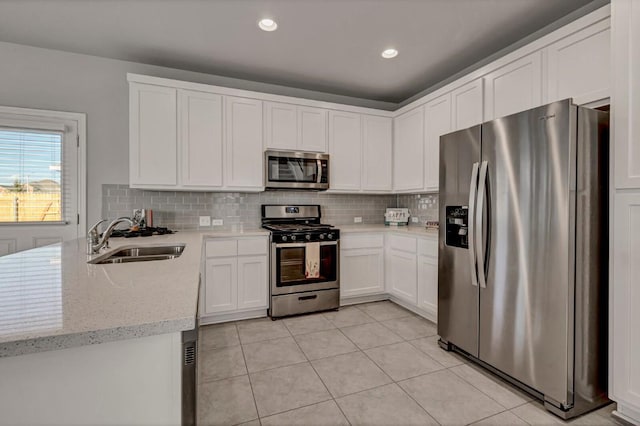 2208 Pecan Island Dr, Leander, TX 78641 - kitchen with appliances with stainless steel finishes, a peninsula, white cabinetry, light tile patterned flooring, and tasteful backsplash