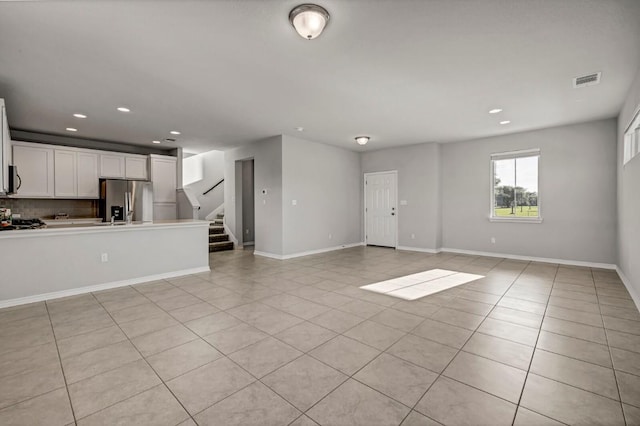 unfurnished living room featuring visible vents, recessed lighting, light tile patterned floors, and stairway