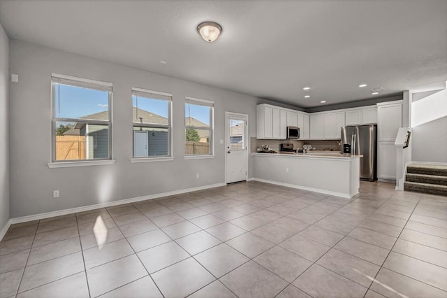 kitchen with stainless steel appliances, white cabinetry, light tile patterned flooring, and open floor plan