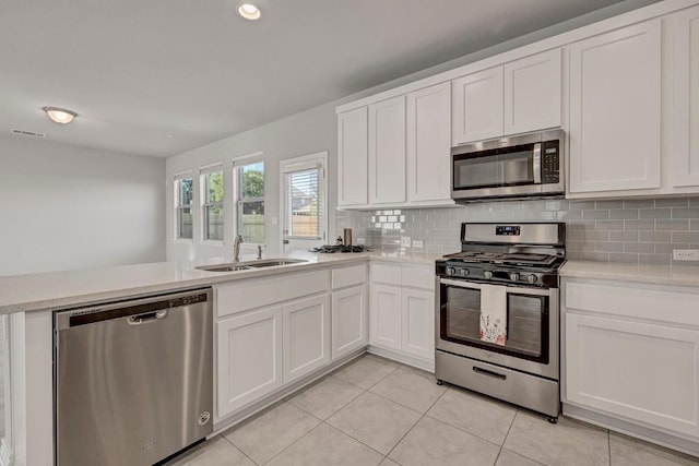 kitchen featuring a sink, light countertops, stainless steel appliances, a peninsula, and decorative backsplash