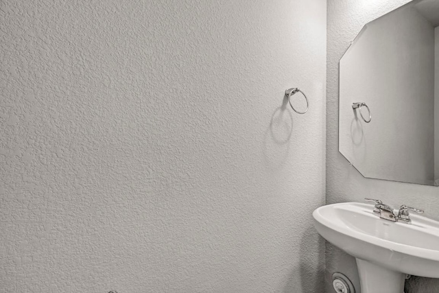 bathroom featuring a textured wall and a sink