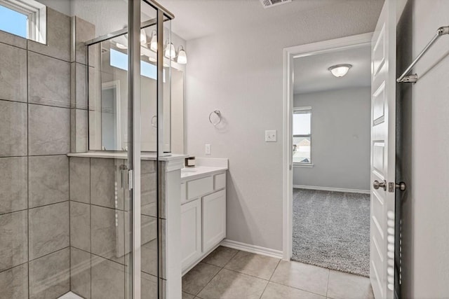 bathroom featuring visible vents, a shower stall, vanity, baseboards, and tile patterned floors