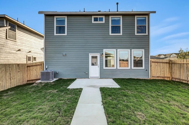 rear view of property featuring a lawn, a patio, central AC unit, and a fenced backyard