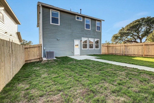 back of property with a fenced backyard, central AC unit, and a yard