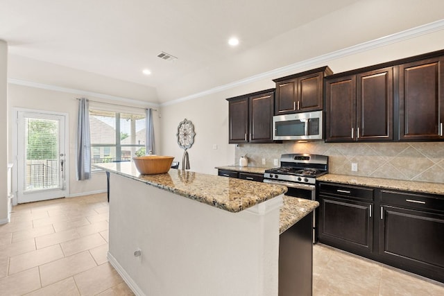 kitchen featuring appliances with stainless steel finishes, tasteful backsplash, visible vents, and a center island