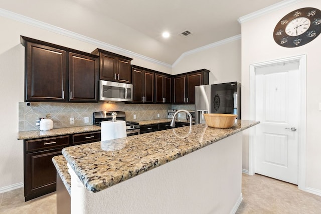 kitchen featuring decorative backsplash, appliances with stainless steel finishes, dark brown cabinets, a sink, and light stone counters
