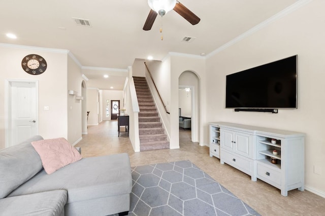 living area featuring crown molding, a ceiling fan, stairs, and arched walkways