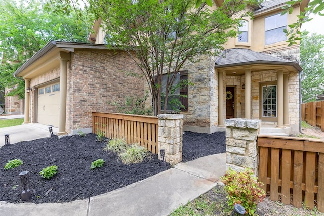 view of front facade featuring fence, stone siding, brick siding, a garage, and driveway