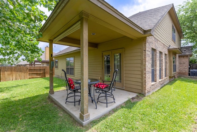rear view of house with roof with shingles, fence, a patio area, and brick siding
