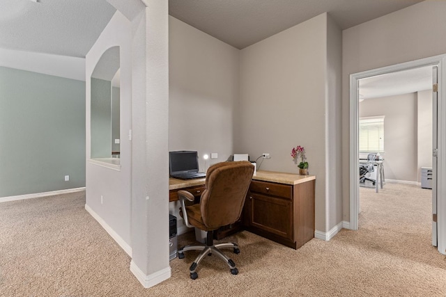 home office with arched walkways, baseboards, and light carpet
