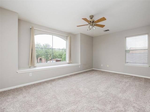 carpeted spare room featuring baseboards, ceiling fan, and visible vents