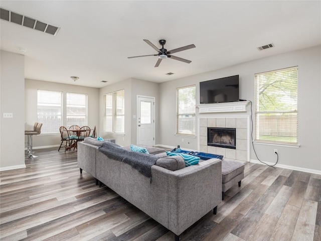 living area with visible vents, a ceiling fan, baseboards, and wood finished floors