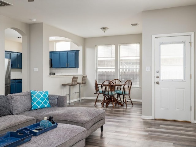 living area with visible vents, arched walkways, baseboards, and wood finished floors