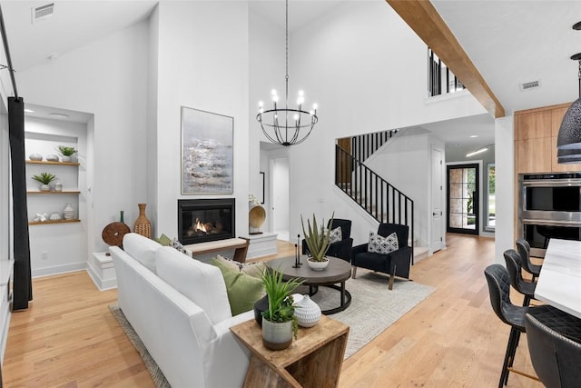 living area featuring visible vents, light wood finished floors, and a towering ceiling