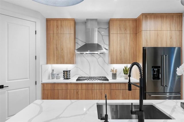 kitchen featuring a sink, modern cabinets, stainless steel appliances, and wall chimney exhaust hood