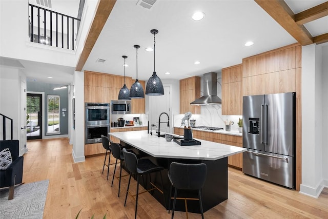 kitchen with modern cabinets, a breakfast bar area, wall chimney range hood, tasteful backsplash, and stainless steel appliances