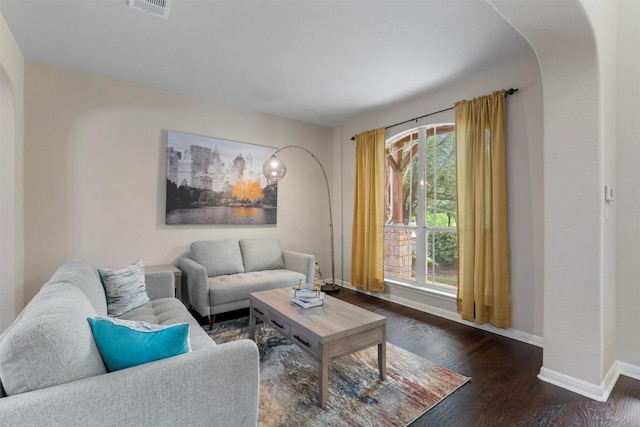 living room with arched walkways, wood finished floors, and baseboards
