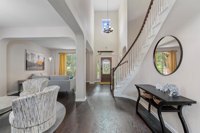 entrance foyer featuring stairs, a chandelier, dark wood-type flooring, and baseboards