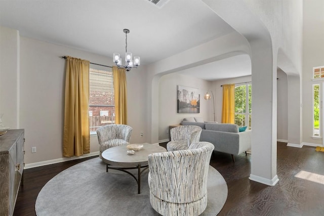 dining area with arched walkways, dark wood-style floors, a chandelier, and baseboards