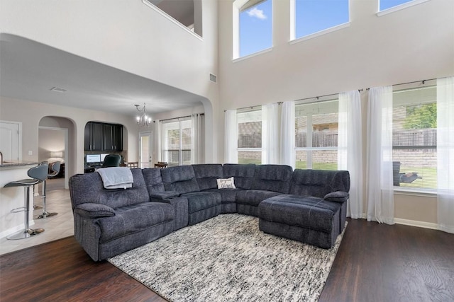 living room with arched walkways, a chandelier, dark wood-style flooring, and baseboards