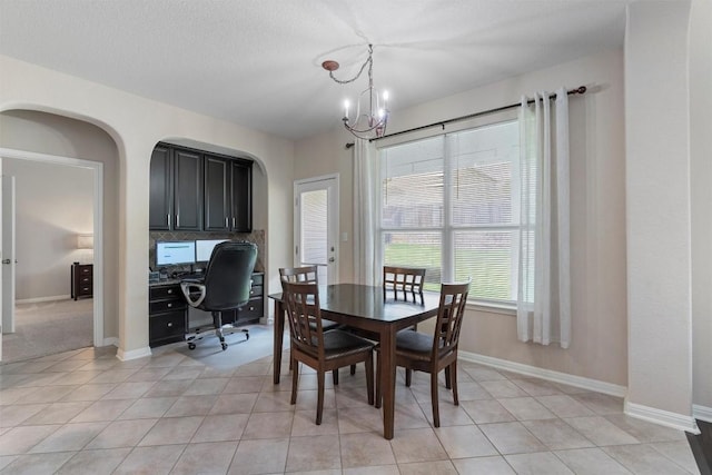 dining room with a chandelier, baseboards, a desk, and arched walkways