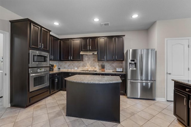 kitchen with appliances with stainless steel finishes, under cabinet range hood, decorative backsplash, light tile patterned flooring, and recessed lighting