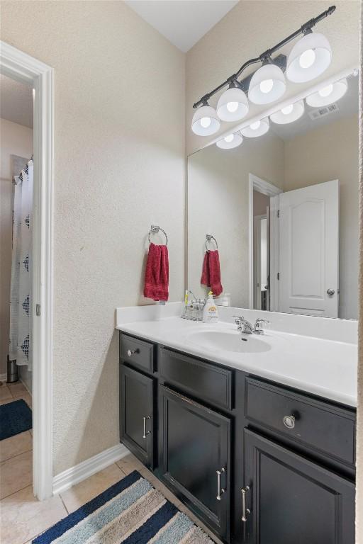 full bath featuring tile patterned flooring, vanity, and baseboards