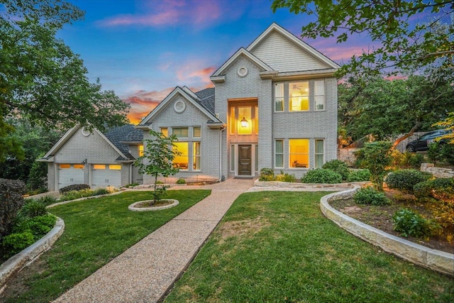 traditional home featuring brick siding, an attached garage, and a yard