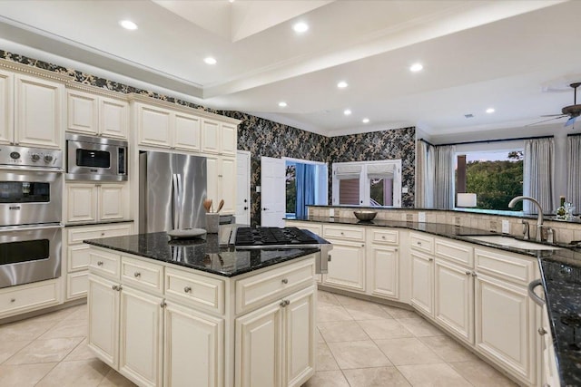 kitchen featuring a center island, cream cabinets, a sink, appliances with stainless steel finishes, and light tile patterned floors