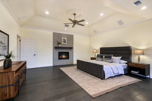 bedroom with a tiled fireplace, lofted ceiling, dark wood finished floors, and visible vents