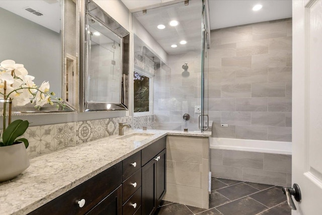 bathroom with vanity, decorative backsplash, tile patterned flooring, tiled shower, and tiled tub