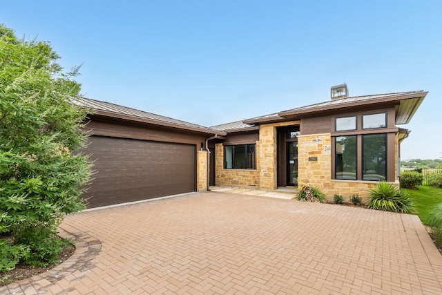 2317 Kahala Sunset Dr, Spicewood, TX 78669 - prairie-style home featuring a standing seam roof, metal roof, decorative driveway, an attached garage, and stone siding